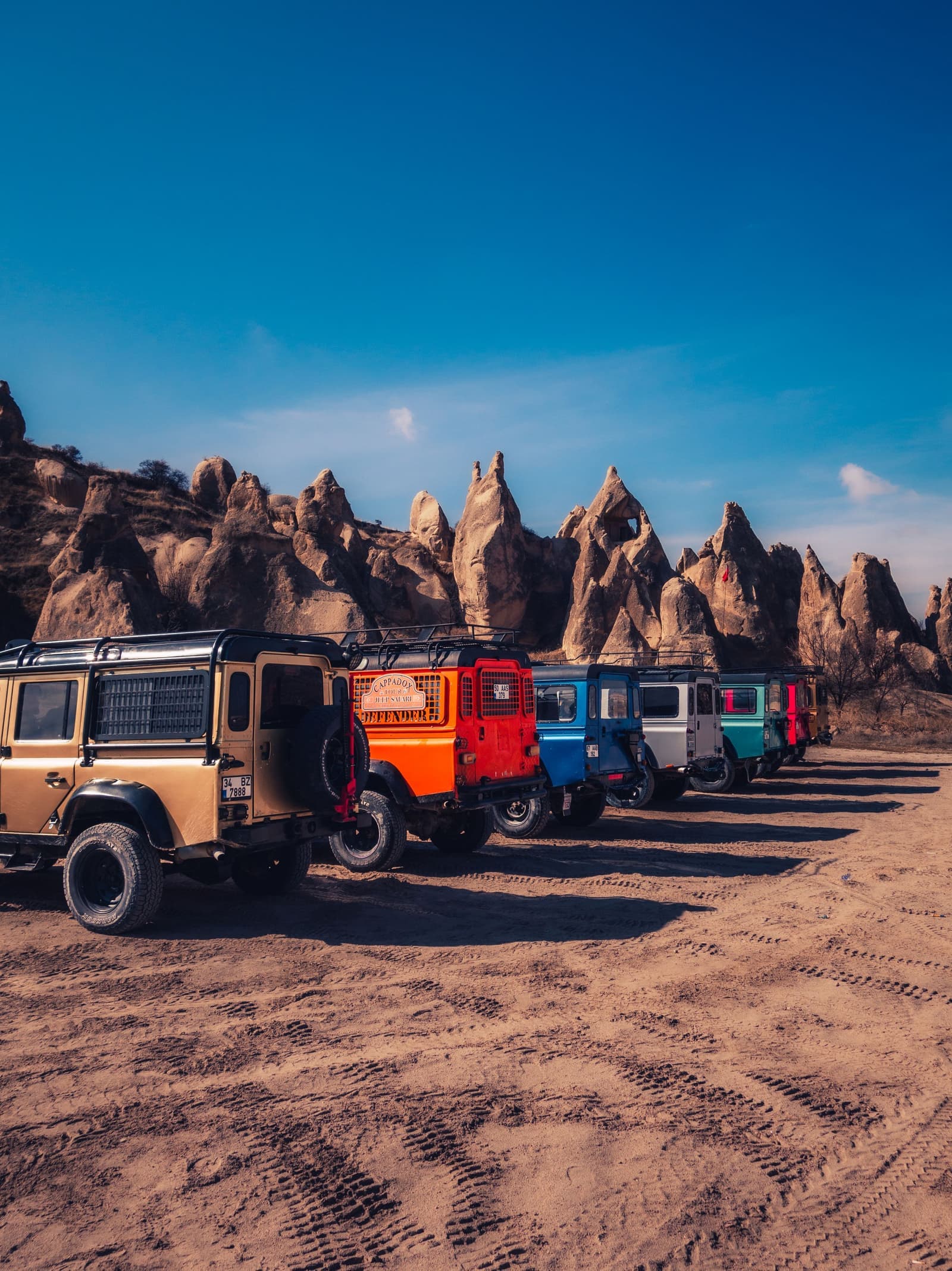 Colourful jeeps lined up in front of Cappadocia's rock formations