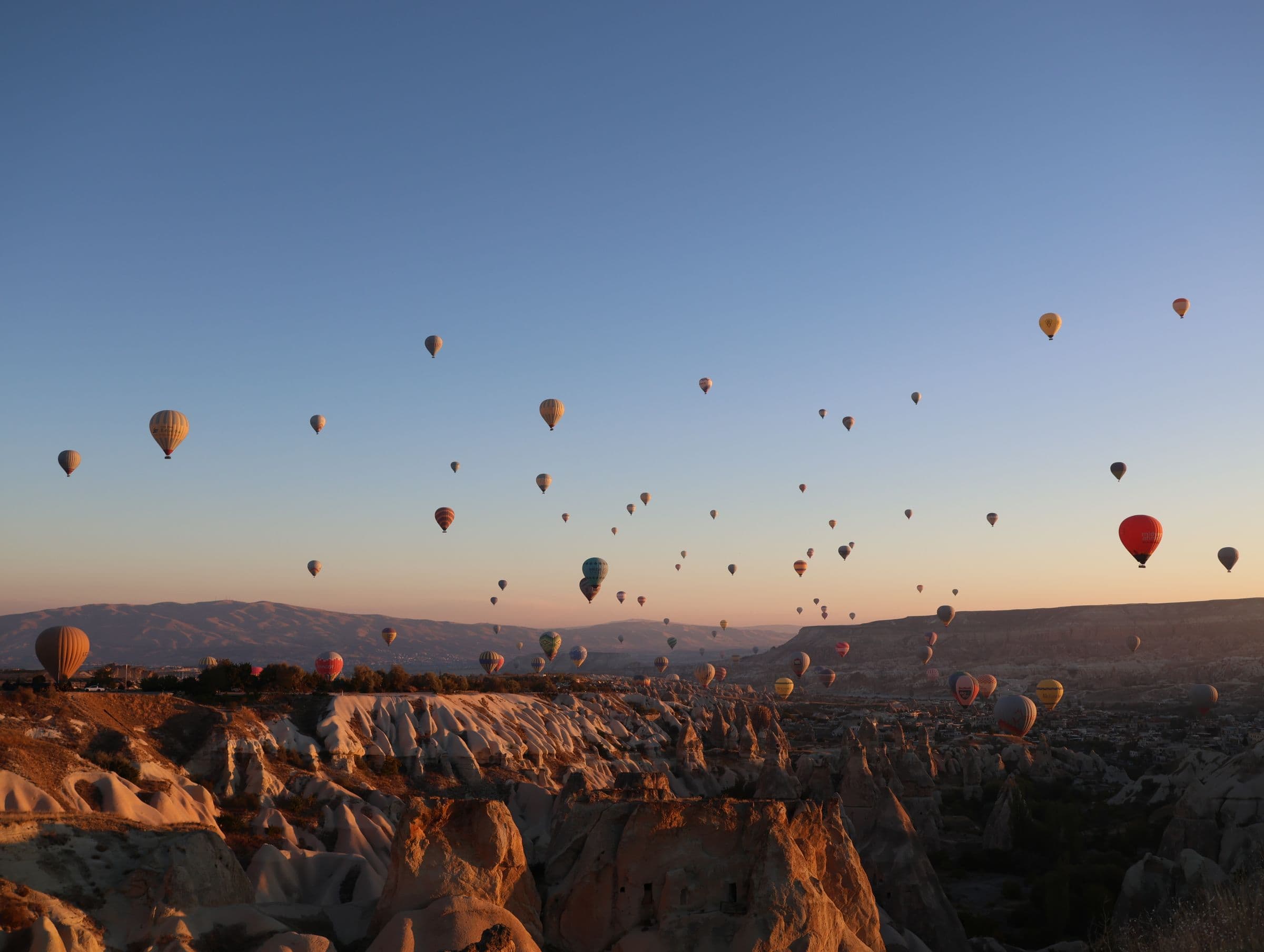 Dozens of hot air balloons over the fairy chimneys of Cappadocia at dawn